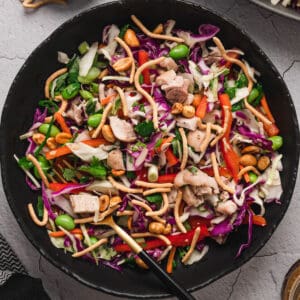 A dark round bowl filled with an Asian chicken salad recipe.