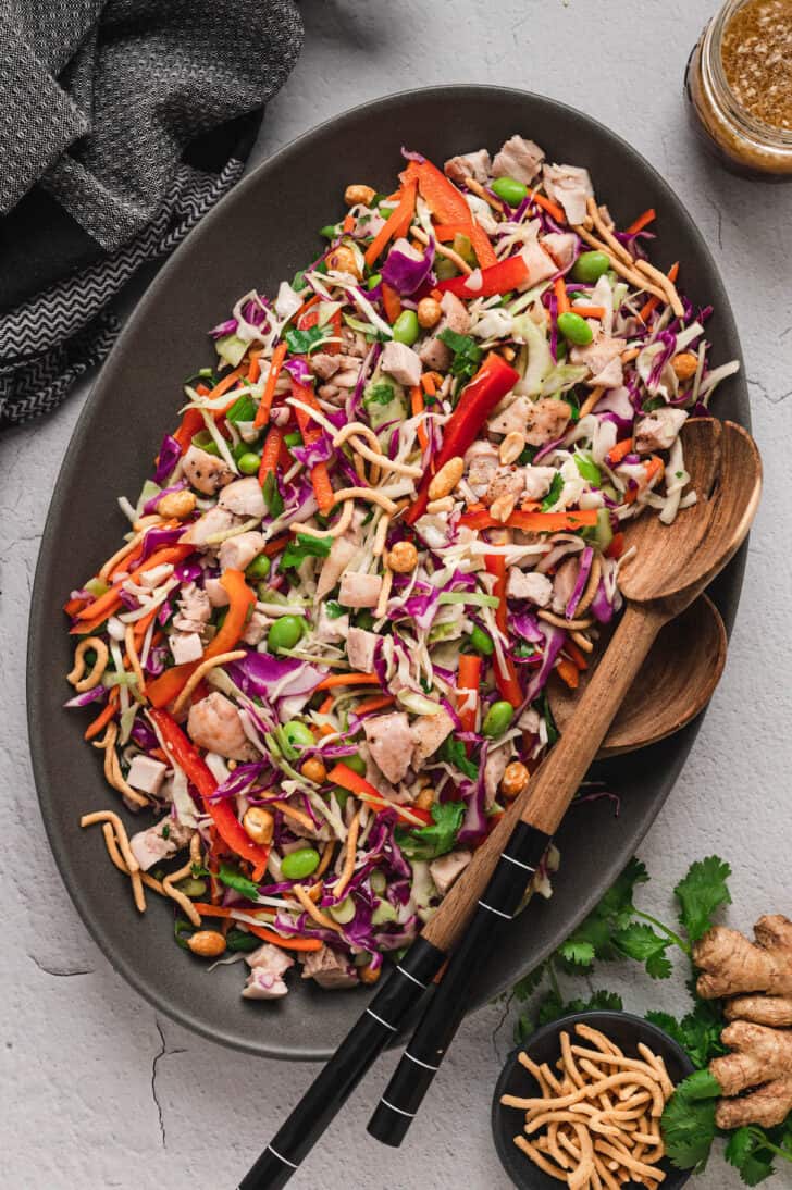 A large oval-shaped dark platter topped with Asian Salad.