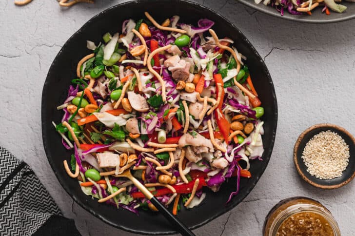 A dark round bowl filled with an Asian salad recipe.