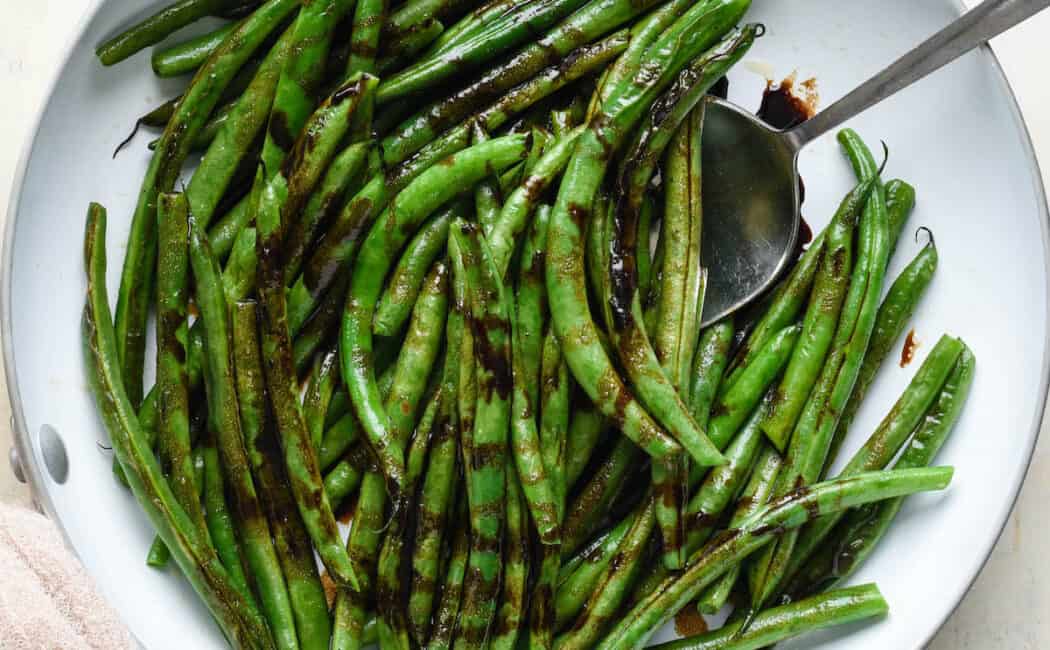 Balsamic green beans in a white skillet.