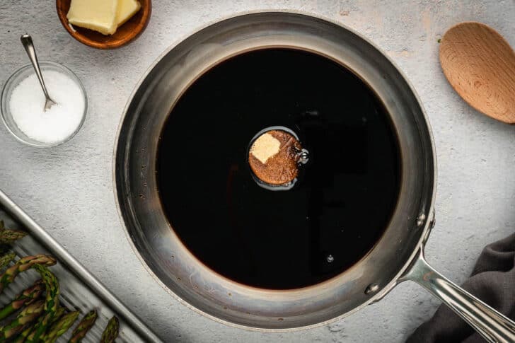 A dark brown reduction with brown sugar being made in a skilet.