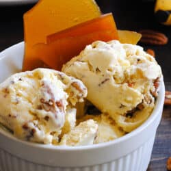 White ceramic bowl filled with nutty homemade ice cream and garnished with brown brittle.