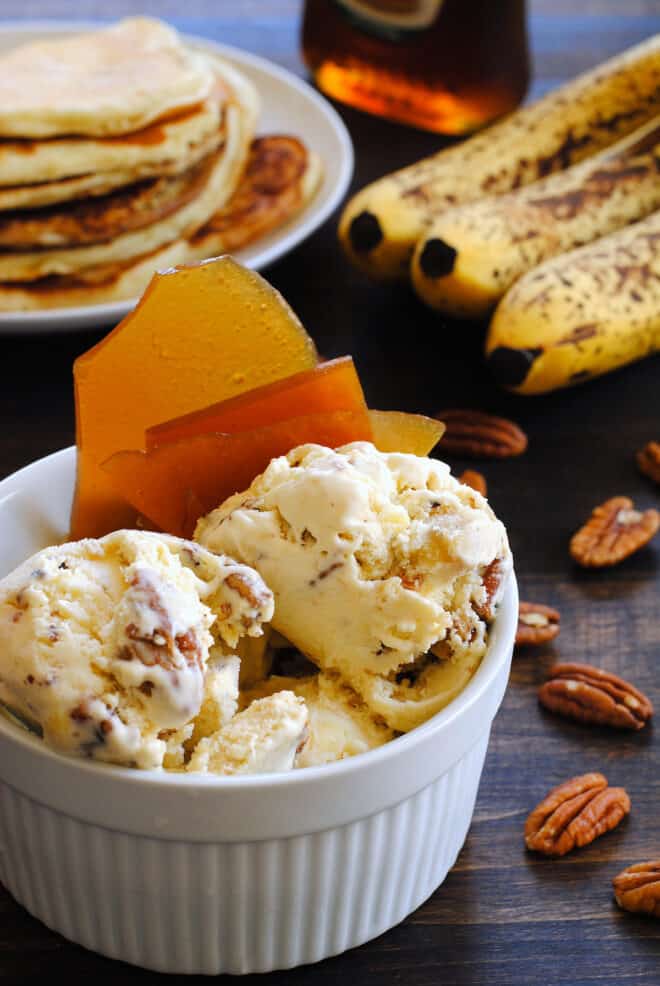 White ceramic bowl filled with nutty homemade ice cream and garnished with brown brittle.