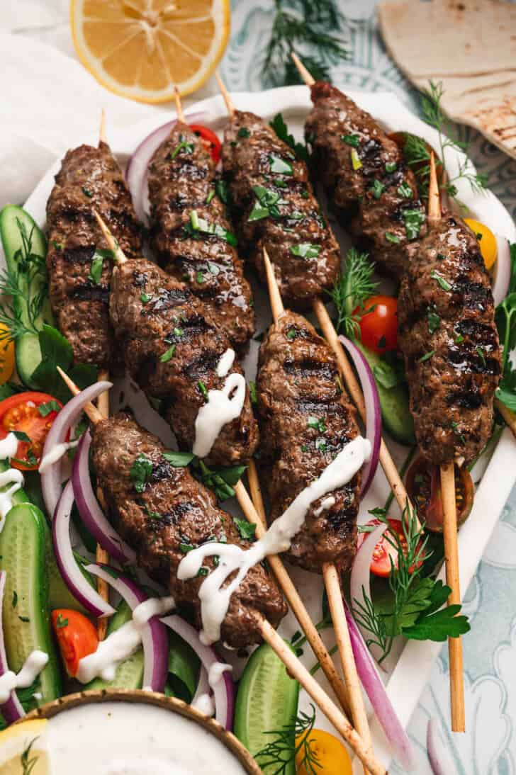 A large platter filled with a kafta recipe, vegetables and a creamy dipping sauce.