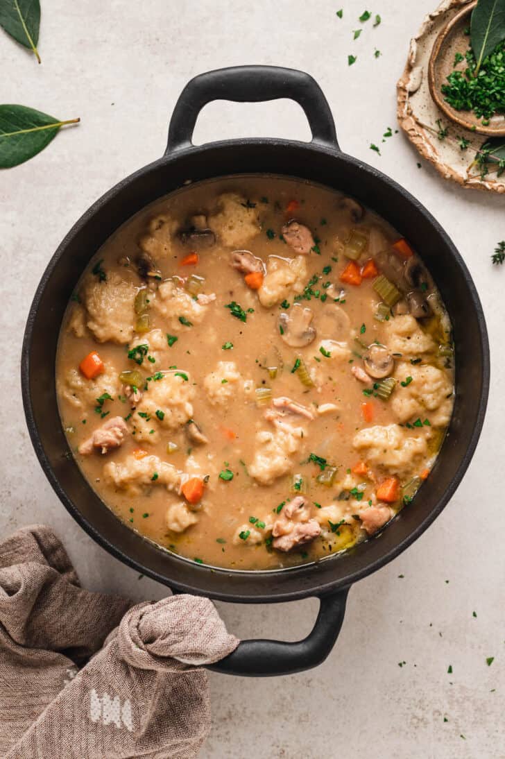 A black cast iron dutch oven filled with the best chicken and dumplings recipe.