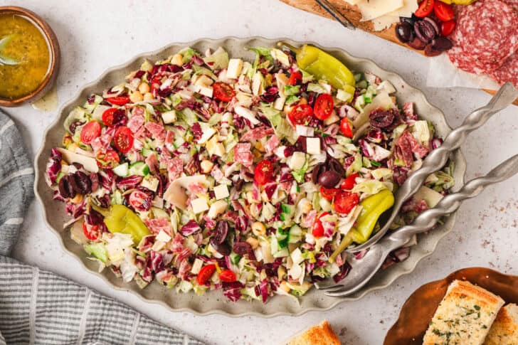 A chopped salad recipe on an oval platter with ruffled edges.