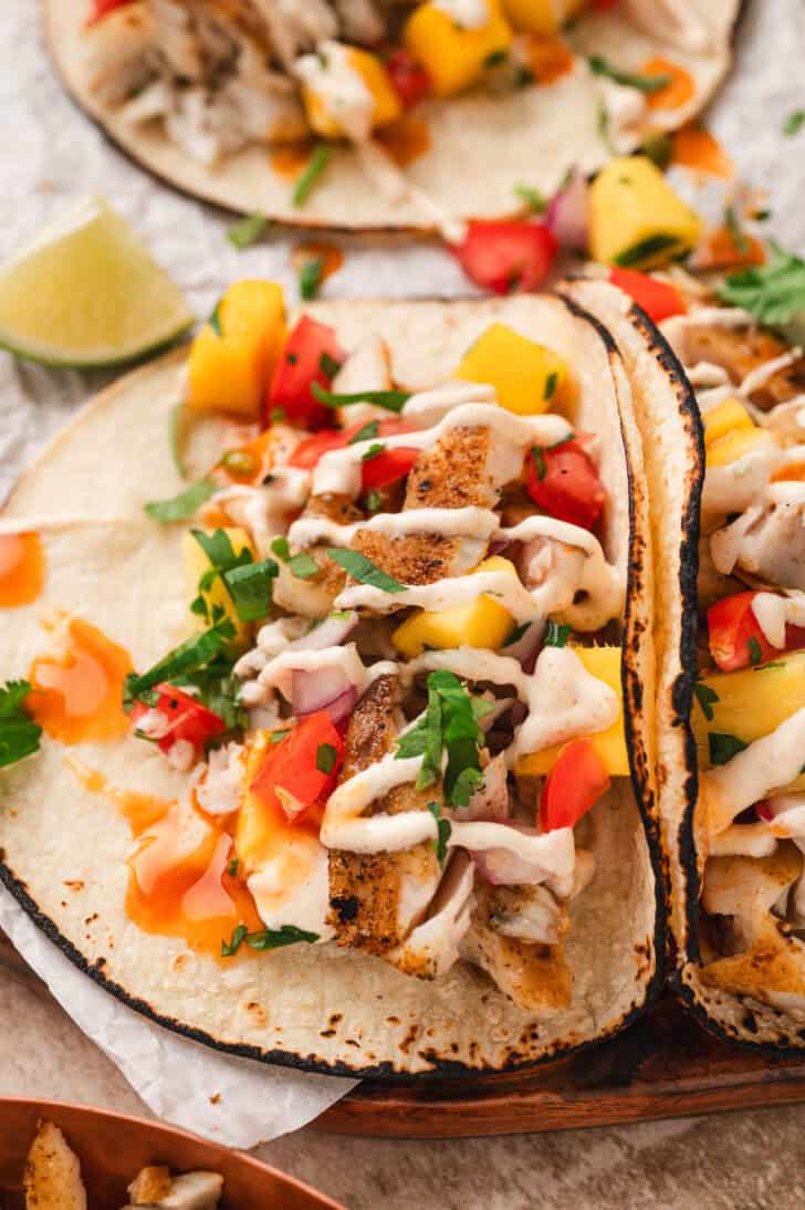 A fish taco topped with tropical fruit salsa and drizzled with creamy sauce.