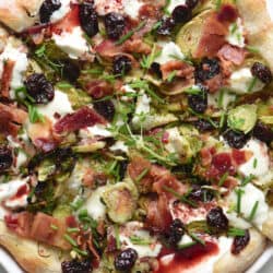 A rustic looking pizza, with Brussels sprouts on pizza, along with bacon, herbs and cherry glaze.