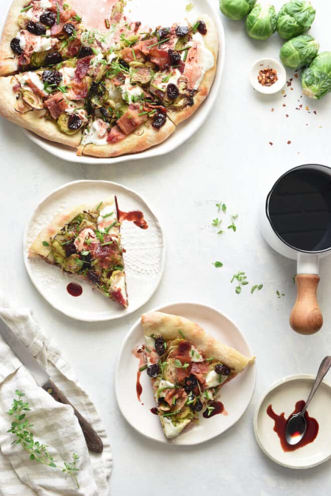 A tabletop scene of flatbread being served onto small plates, with a cherry reduction sauce for drizzling.