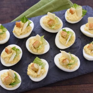 Caesar Salad Deviled Eggs - For this fun take on deviled eggs, egg yolks are mixed with classic Caesar salad flavors and Greek yogurt. If desired, garnish with lettuce, shaved Parmesan cheese and a crouton! | foxeslovelemons.com