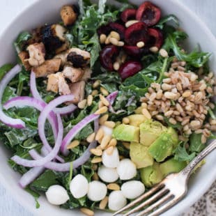 Chicken & Cherry Chopped Kale Salad with Pesto Ranch Dressing - A colorful and delicious mix of greens, chicken, cherries, farro, avocado, mozzarella cheese, red onions and pine nuts, tossed with homemade pesto ranch dressing! | foxeslovelemons.com