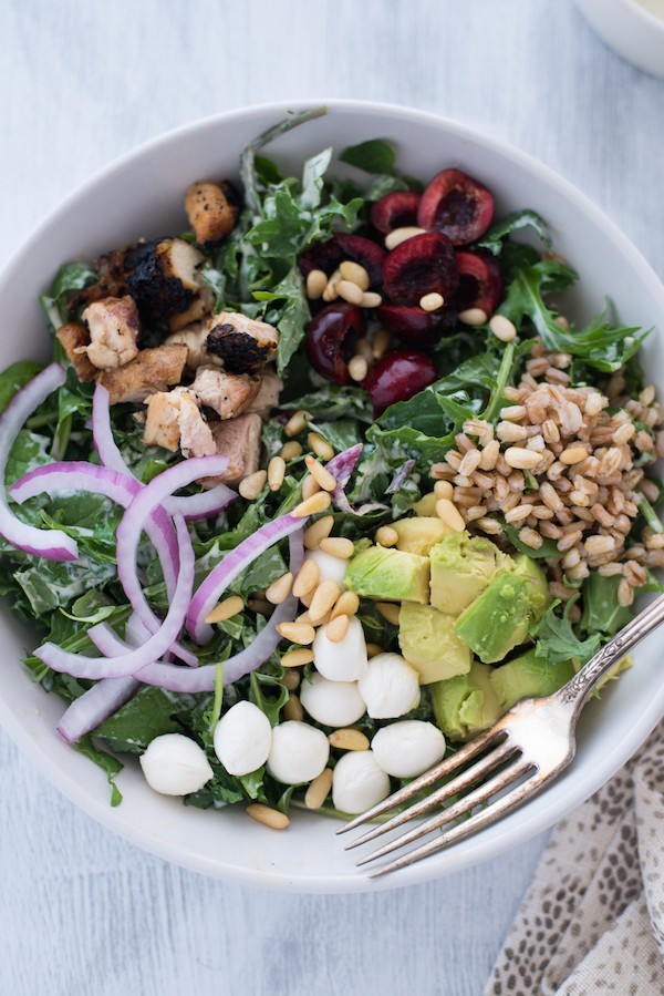 Chicken & Cherry Chopped Kale Salad with Pesto Ranch Dressing - A colorful and delicious mix of greens, chicken, cherries, farro, avocado, mozzarella cheese, red onions and pine nuts, tossed with homemade pesto ranch dressing! | foxeslovelemons.com