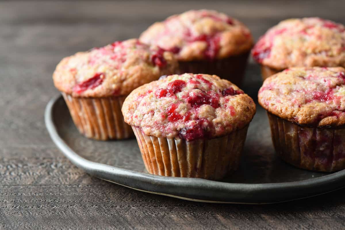 Five cranberry muffins on a gray plate.