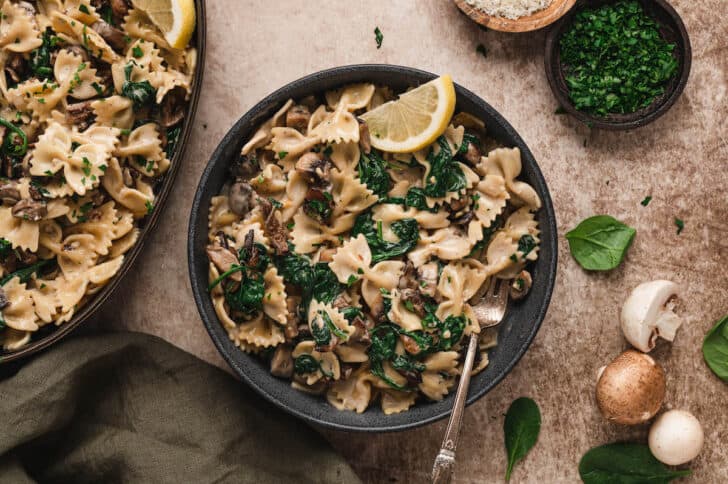 A dark bowl filled with creamy garlic mushroom pasta.