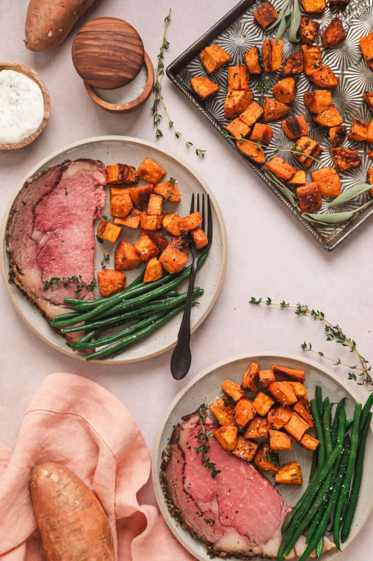 Dinner plates filled with prime rib, green beans and oven roasted sweet potatoes.