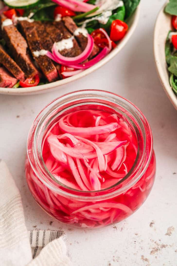 A glass jar filled with quick pickled red onion.