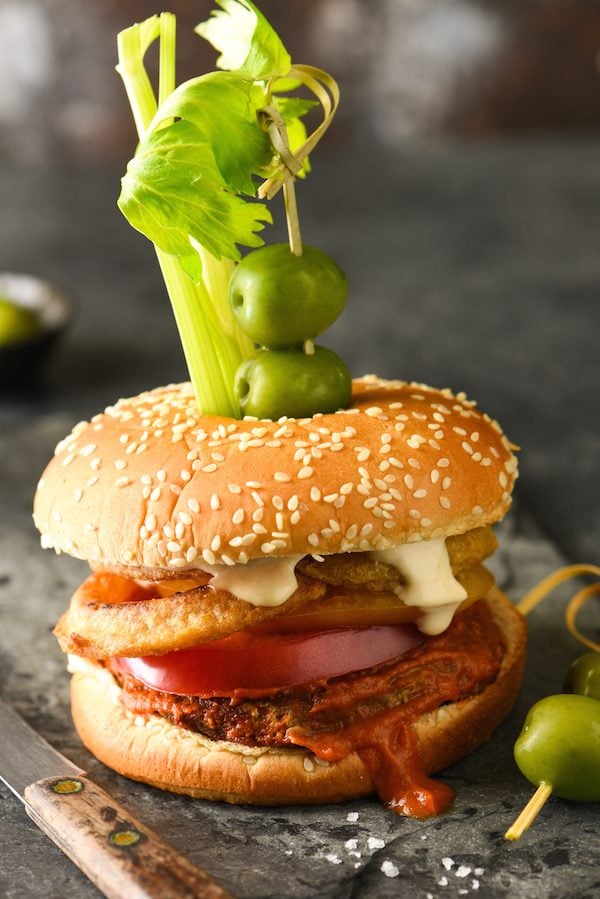 Epic Bloody Mary Burgers - Bloody mary lovers, this burger is calling your name! The burger is slathered in bloody mary ketchup, then topped with onion rings, tomato slices and horseradish mayo. Skewer with celery, olives and pickles and dig in! | foxeslovelemons.com