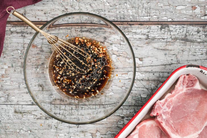 A soy sauce and garlic mixture being whisked together in a glass bowl.