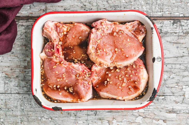 Raw pieces of meat in a baking dish covered in marinade.