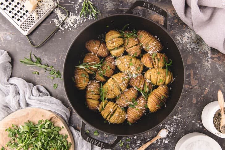 Mini hasselback potatoes sprinkled with cheese.