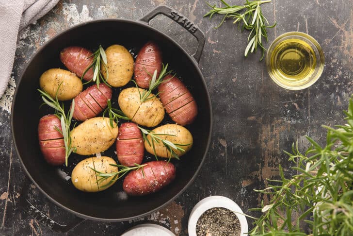 A hasselback potatoes recipe in a cast iron roasting dish, ready for the oven.