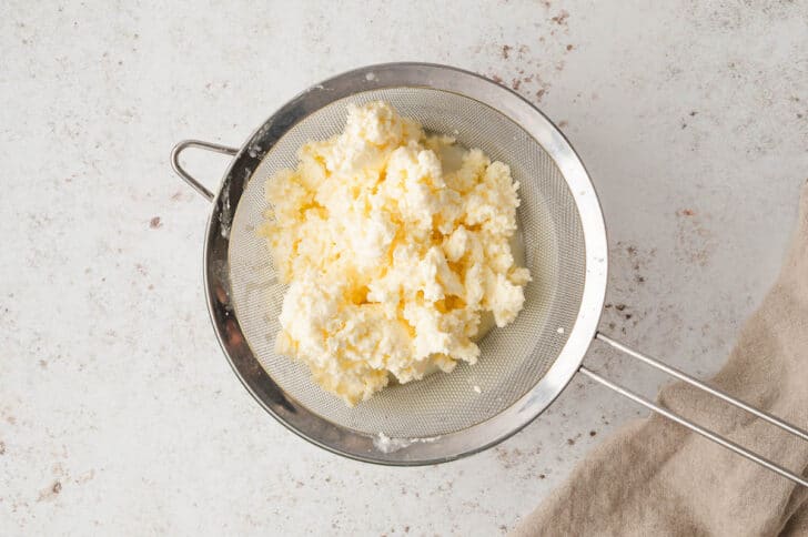 A stainless steel strainer filled with homemade butter.