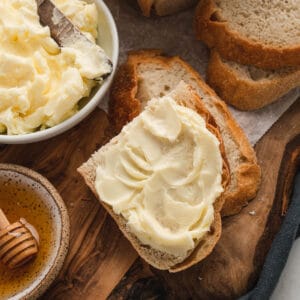 Bread spread with homemade butter on a rustic wooden cutting board.