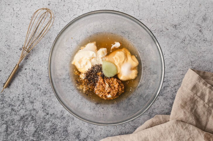 A glass bowl filled with several white and beige and brown liquid ingredients.