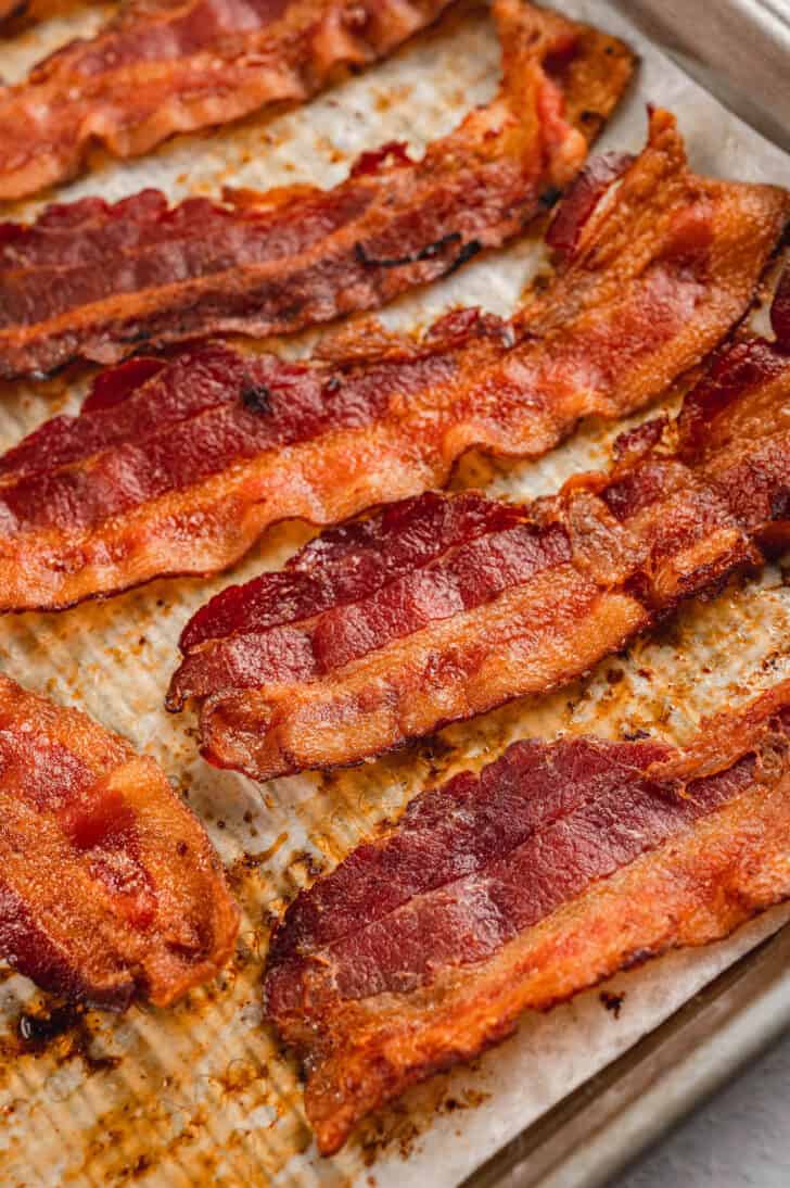 Slices of crispy cured pork on a baking pan.