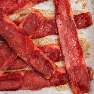 Oven baked turkey bacon slices sitting on top of a rimmed baking pan.