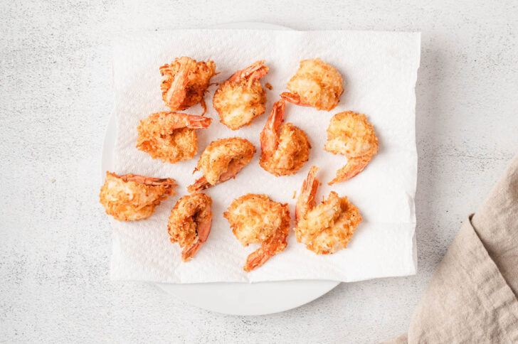 Coconut fried shrimp resting on a paper towel.