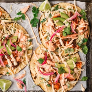 Salmon tacos on a parchment-lined rimmed baking pan.