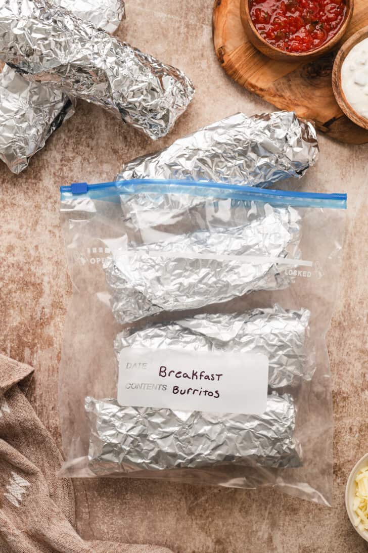 A gallon ziploc bag filled with foil-wrapped burritos, labeled "Breakfast Burritos."