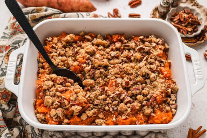 Sweet potato casserole with pecans in a white baking dish.