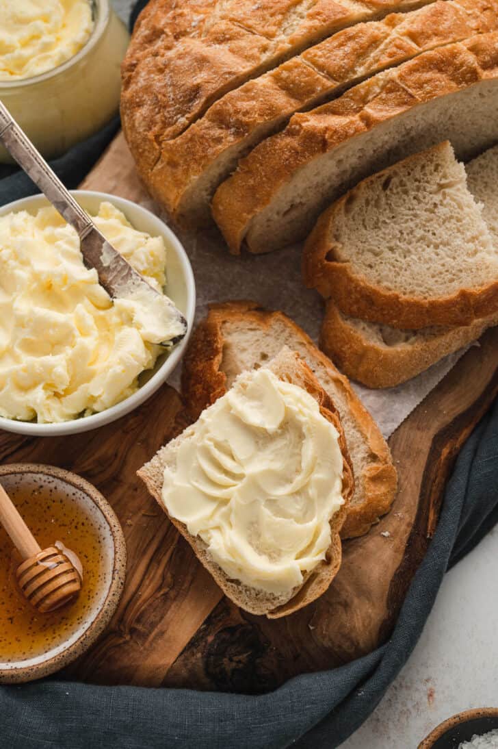 Bread spread with homemade butter on a rustic wooden cutting board.