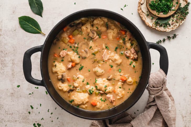 A black cast iron dutch oven filled with old fashioned chicken and dumplings.