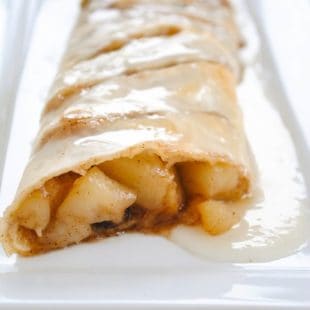 Sliced pear strudel on rectangle white platter.