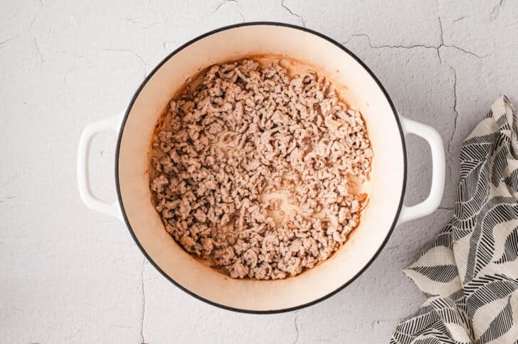 A white Dutch oven filled with cooked ground meat.