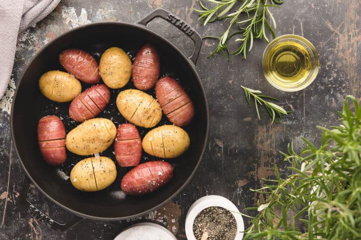 A hasselback potatoes recipe in a cast iron roasting dish, ready for the oven.