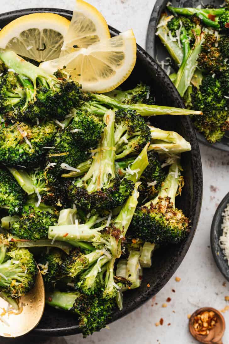 A black bowl filled with roasted vegetables topped with cheese.