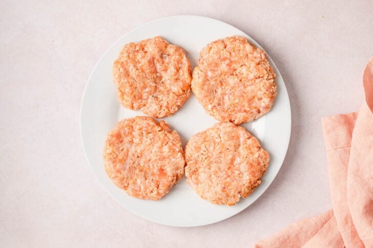 Four fish patties on a white plate.