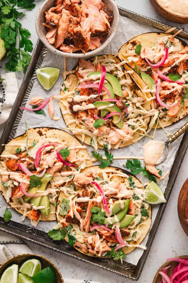 Salmon tacos on a parchment-lined rimmed baking pan.