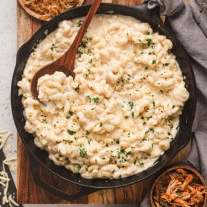 Stovetop mac and cheeses in a cast iron skillet, surrounded by various mix-in ingredients.