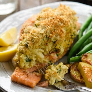 Closeup on piece of crab stuffed salmon topped with breadcrumbs, with fork taking a piece.