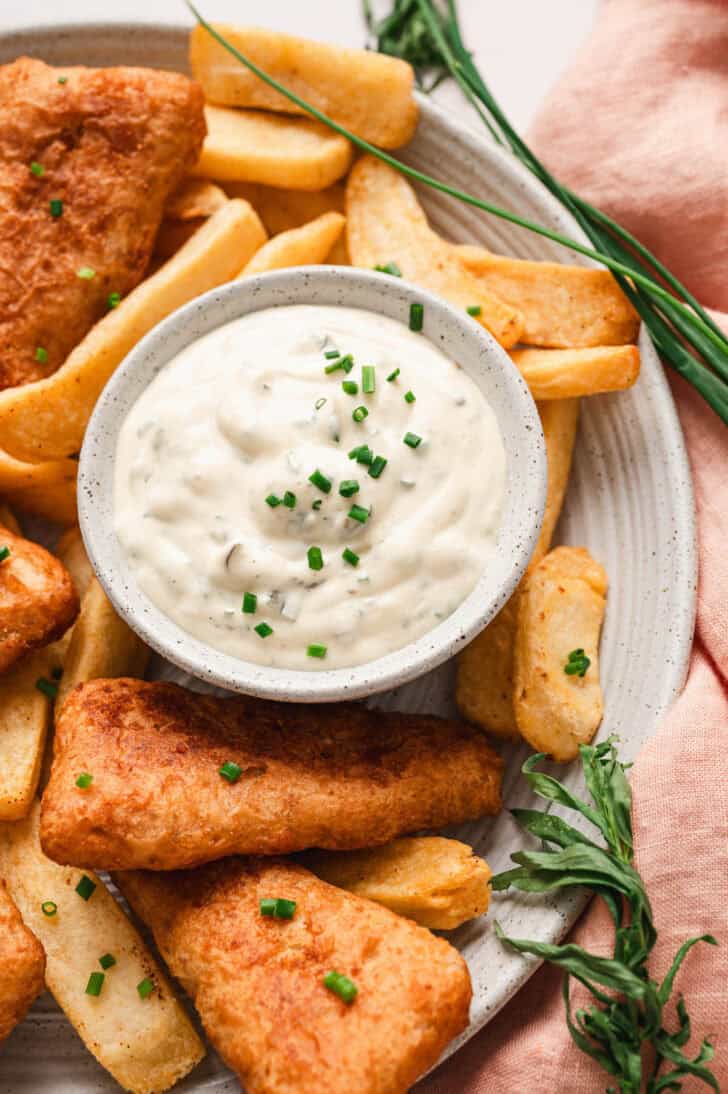 A bowl of tartar sauce recipe easy on a plate with fish and chips.