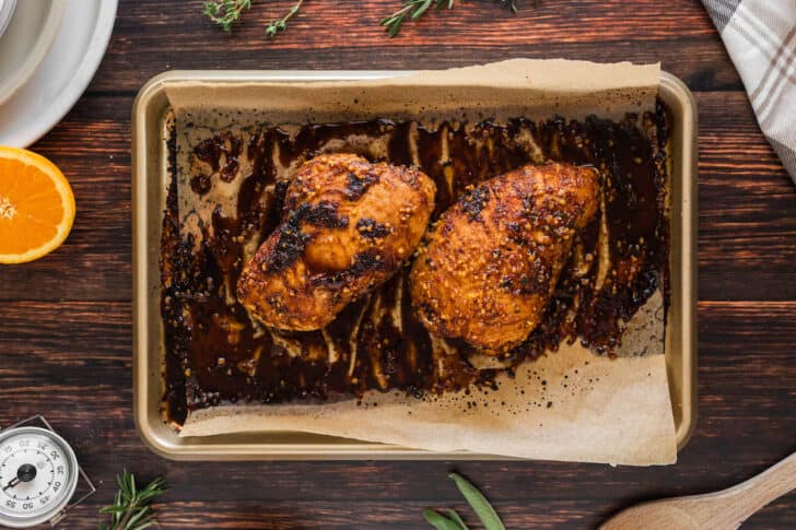 A recipe for turkey breast tenderloin that has come out of the oven on a rimmed baking pan.