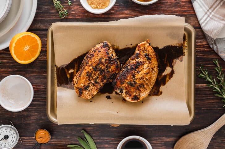 A recipe for turkey tenderloin being baked on a rimmed baking pan lined with parchment paper.