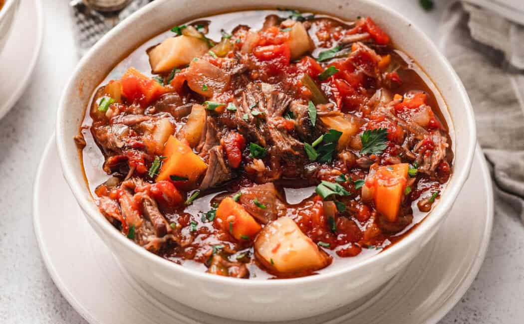 Crockpot vegetable beef soup in a white bowl.